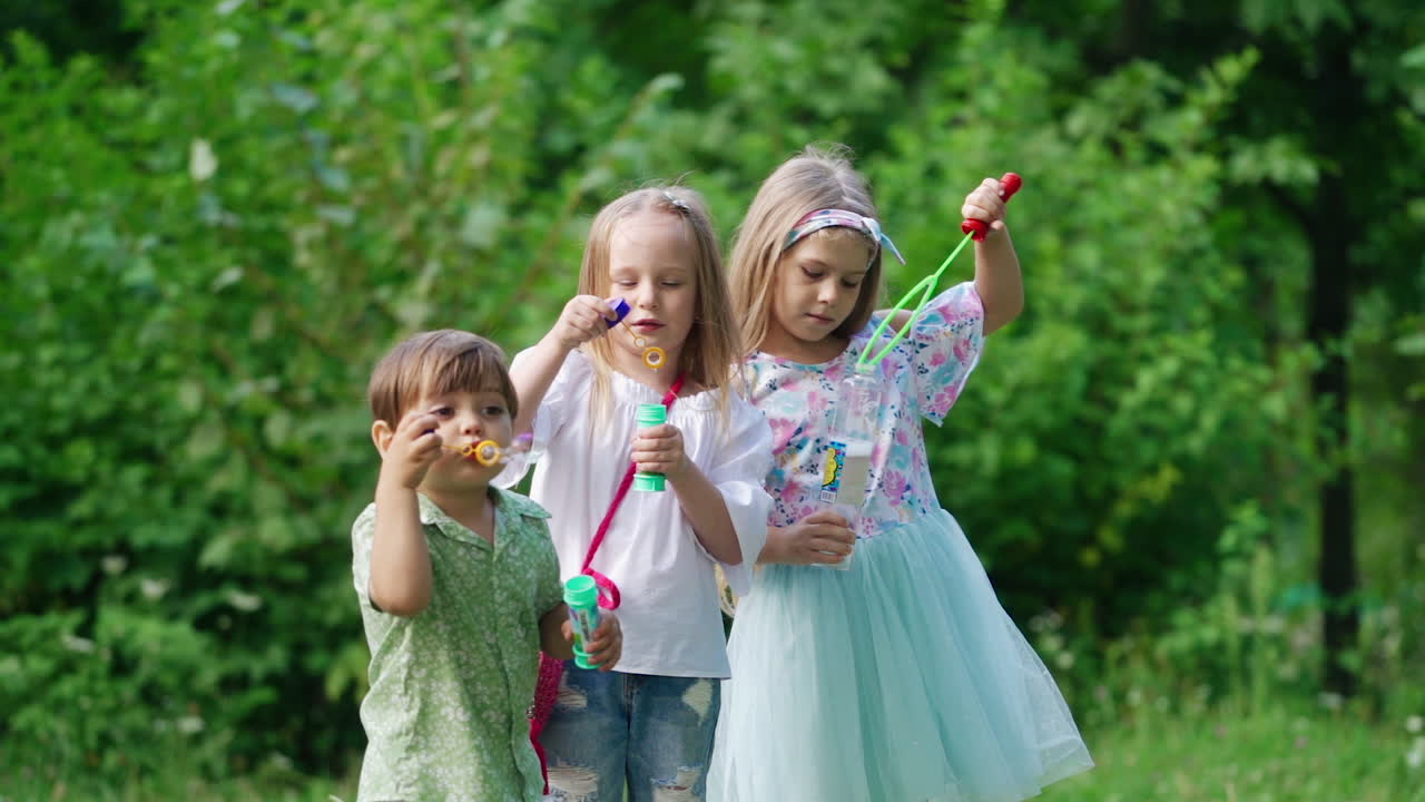 Happy kids in the park. Little girls blowing soap bubbles in park