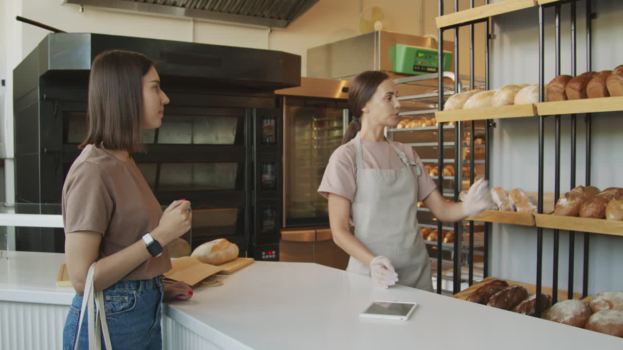 Addetto al banco della panetteria che parla con un cliente