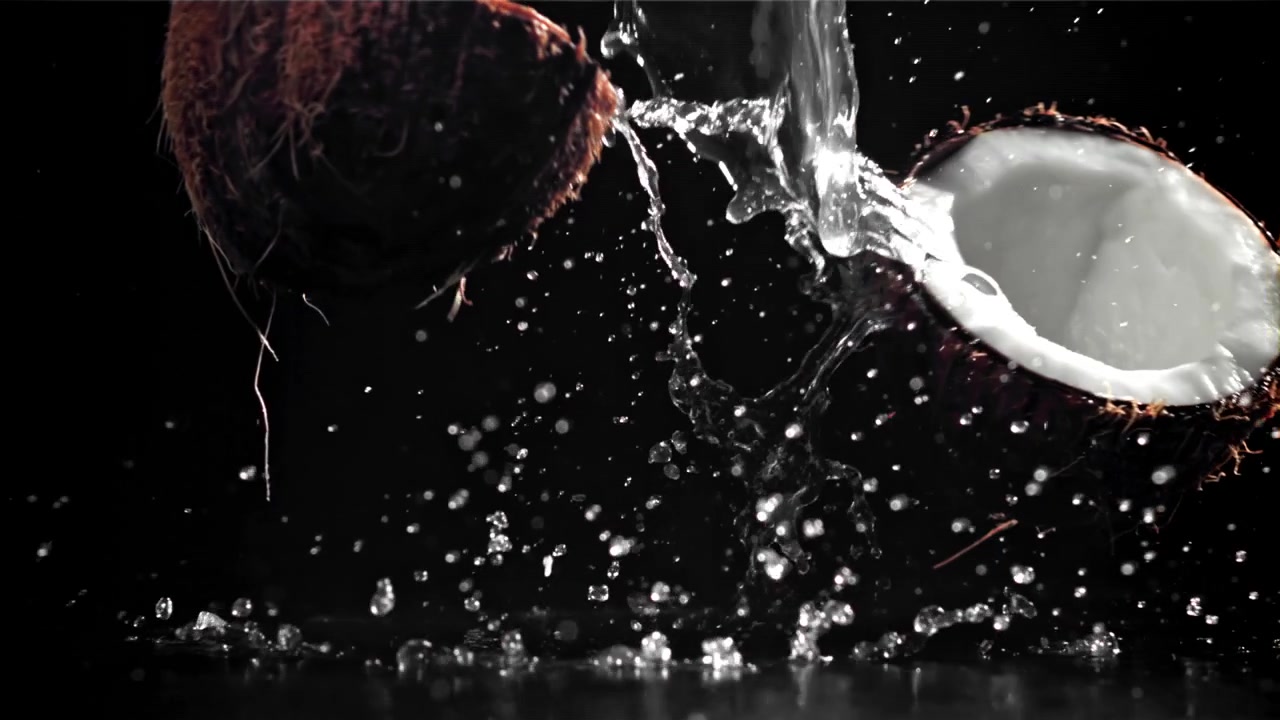 Slow Motion Coconut Splitting and Water Splashing on Black Background