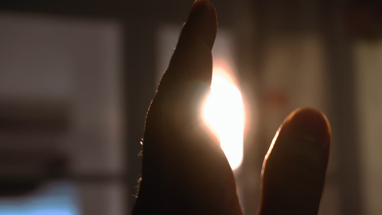 mira la puesta de sol a través de la mano de la silueta