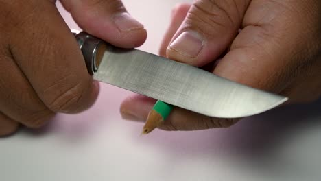 Footage-of-hands-slowly-sharpening-a-pencil-and-some-coloured-pencils-with-a-sharp-knife