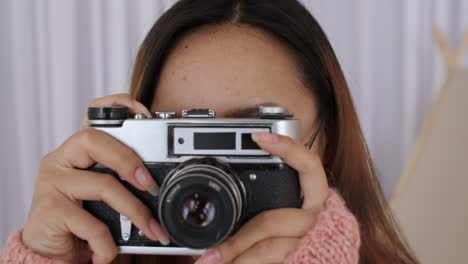 close up of middle eastern young woman face in glasses, girl, student takes pictures on a retro camera, presses the shutter. female photographer picks up the camera and presses button. slow motion