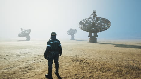 worker standing near large satellite dishes in a foggy landscape