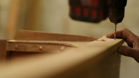 shipwright at work, predrilling covering board for traditional wooden boat
