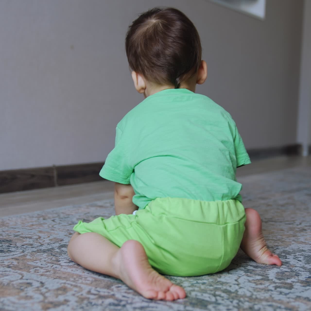 One year old toddler plays with a toy car at home. Rear view of a child having fun