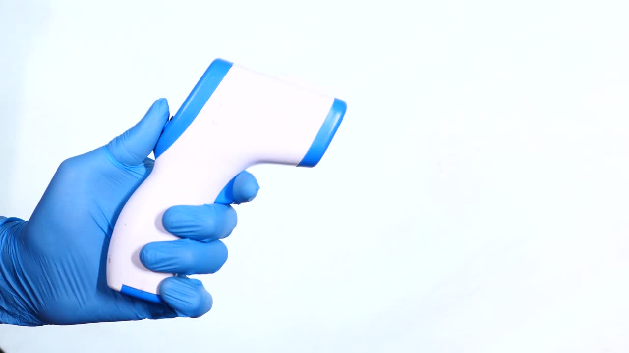 persona con un termómetro sin contacto con guantes azules