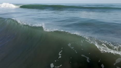 aerial - camera follows deep blue crashing wave