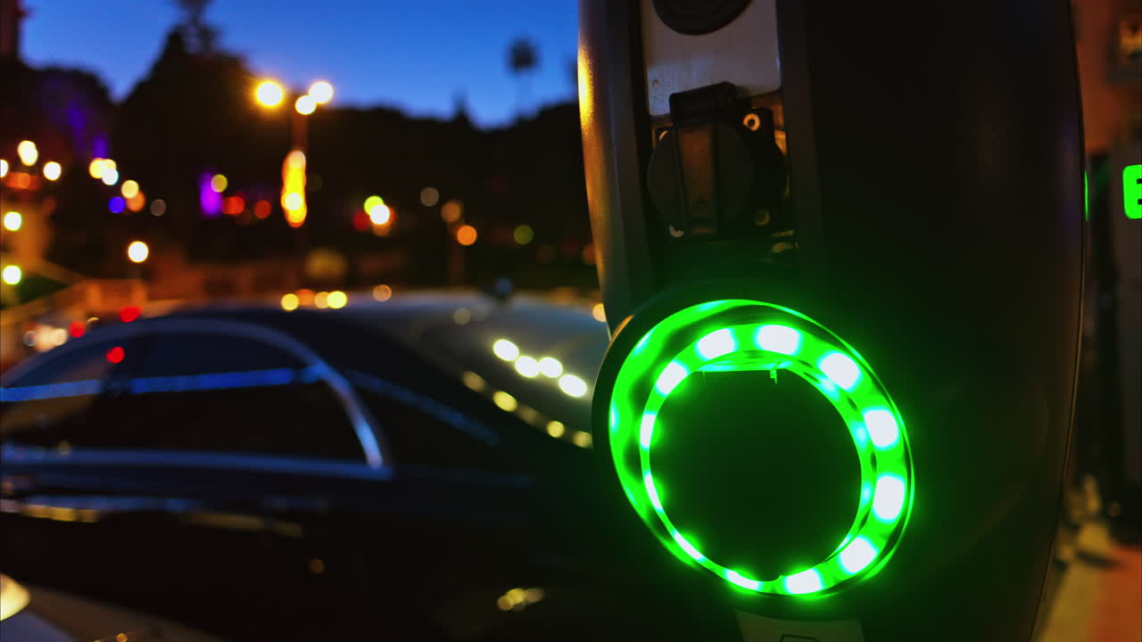 Close up of an illuminated, electric car charging station at night