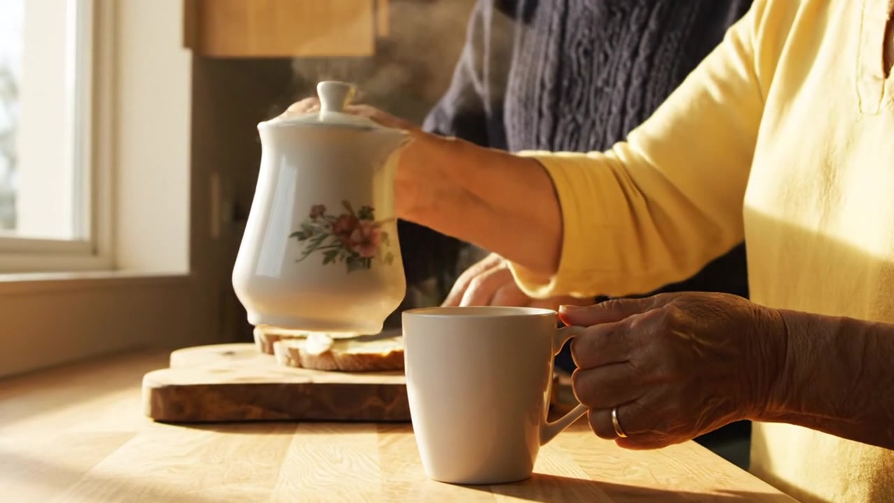 Signora anziana che versa caffè fumante in una tazza di ceramica