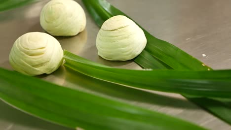 Pastelería-China-Verde-Sobre-Una-Mesa-Decorada-Con-Hojas-De-Pandan,-De-Cerca-1