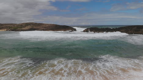 olas rompiendo en rocas cerca de la arena