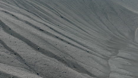 Arena-Oscura,-Textura-De-Ondas-De-Arena-Volcánica-Negra,-Toma-Aérea