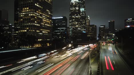 time lapse, downtown los angeles over freeway with traffic, nighttime city view, panning left