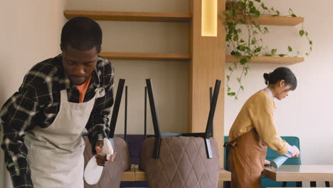 waitress and waiter cleaning coffee shop table with disinfectant spray and rag 1