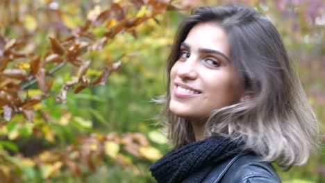 close shot of brunette girl in autumn forest, smiling sweet at camera