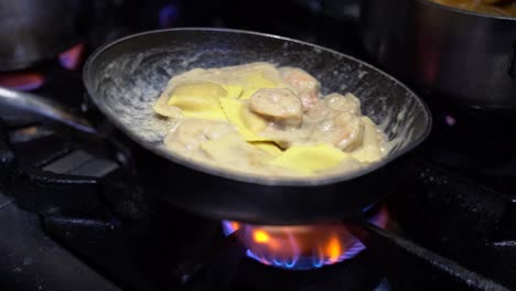 cooking ravioli and shrimp with sour cream in a cooking pan in slow motion