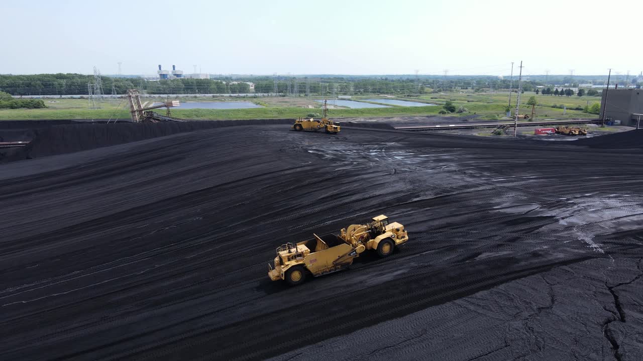 Macchina industriale che movimenta un enorme mucchio di carbone per una centrale elettrica, vista aerea.