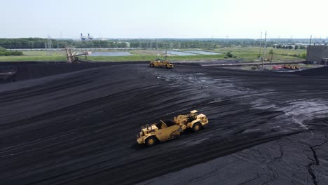 industrial machine grading massive pile of coal for powerplant, aerial view