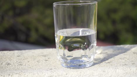 Glas,-Halb-Gefüllt-Mit-Wasser,-Isoliert-Vor-Einem-Unscharfen-Hintergrund,-Langsamer-Zoom