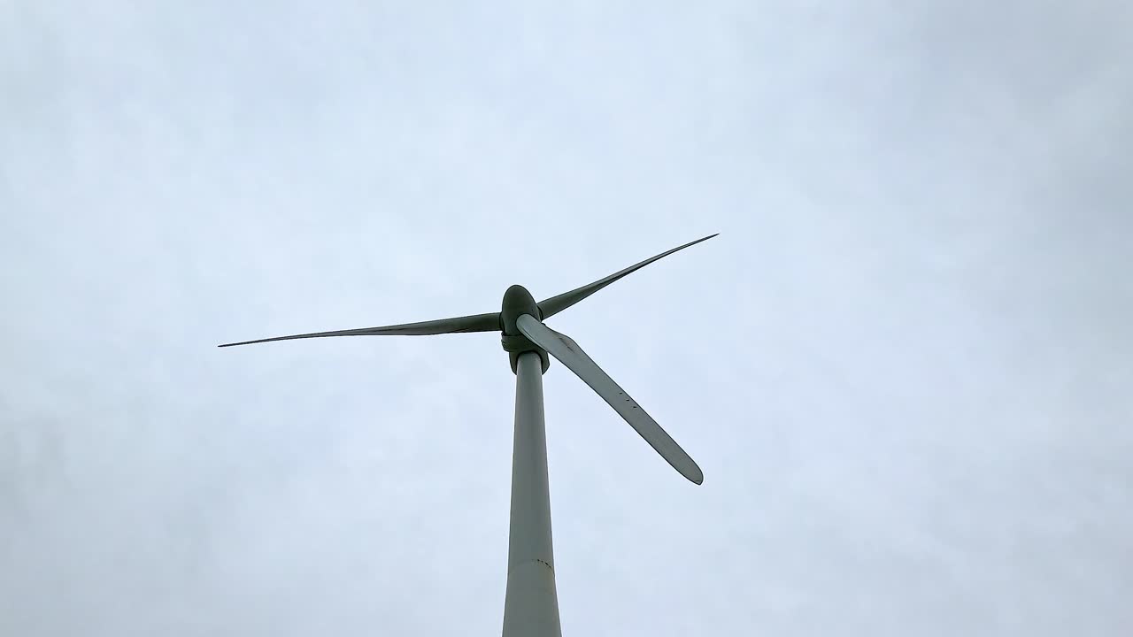 구름이 가득한 하늘을 향해 회전하는 풍차 날개