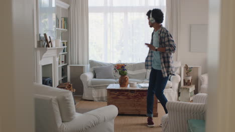 Un-Joven-Feliz-Bailando-En-Casa-Celebrando-El-éxito-Escuchando-Música-Usando-Audífonos-Divirtiéndose-Bailando-En-La-Sala-De-Estar-El-Fin-De-Semana