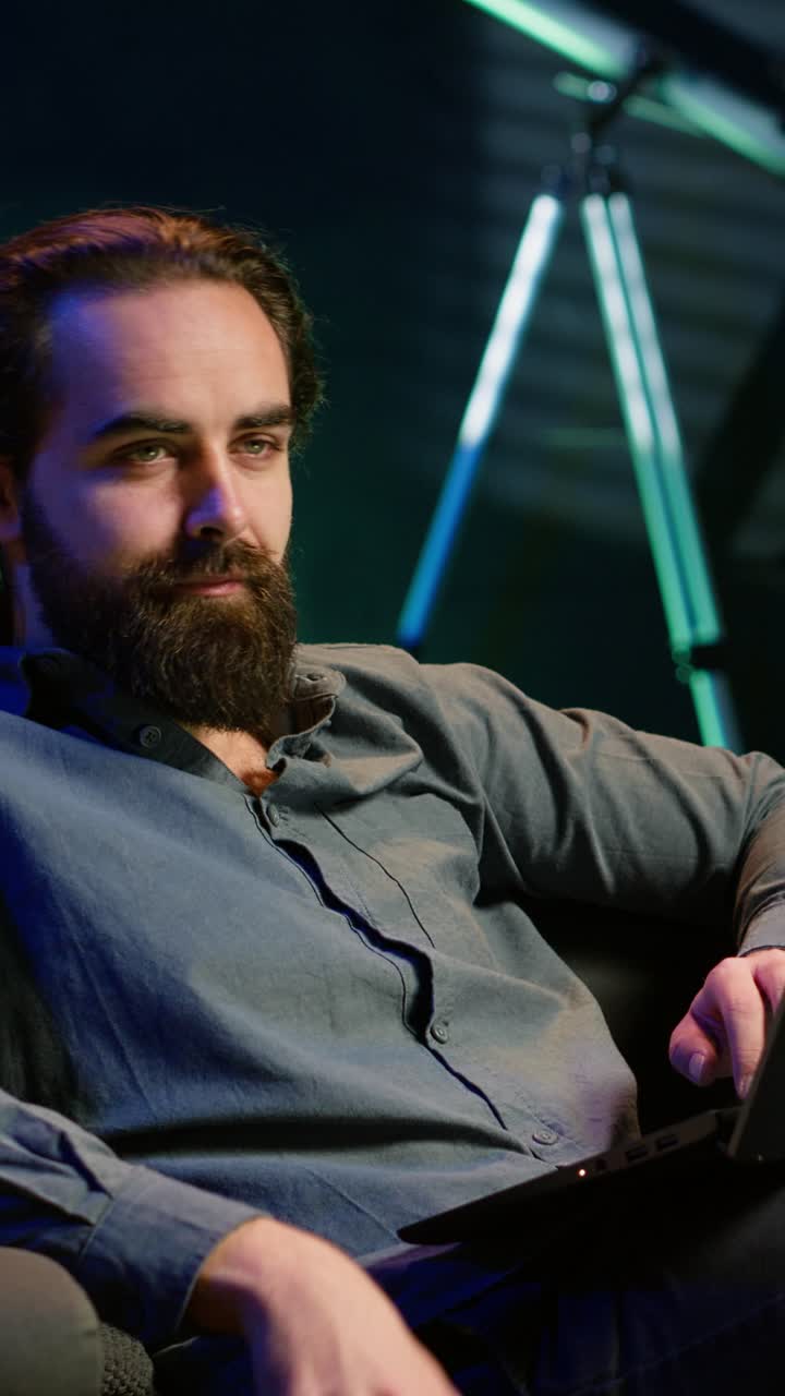 Vertical video Teleworker writing emails on laptop at home while watching TV