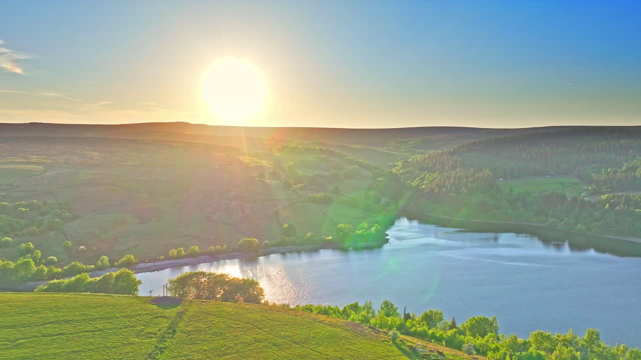 Aerial: Strines Reservoir, water storage reservoir, with forest at sunset near Sheffield, South Yorkshire, England, pull out drone shot