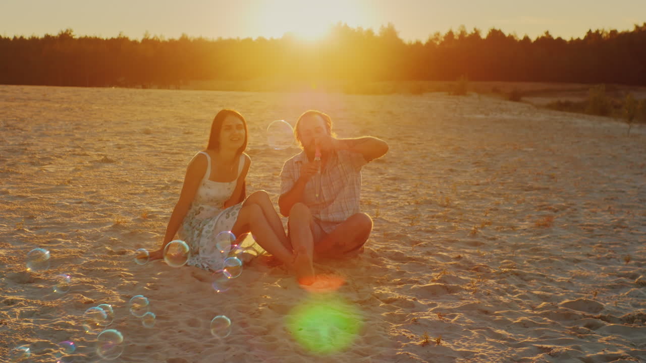 familia joven divirtiéndose con niños - soplar burbujas al atardecer