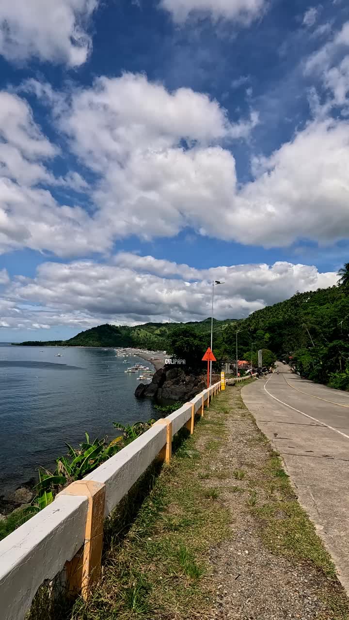 Ponto de vista de caminhada pela estrada costeira ao longo do mar com um céu limpo e nuvens fofas em Culipapa Hinoba-an, Negros Ocidental, Filipinas