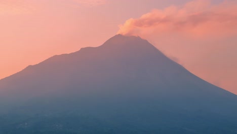 Aerial-view-of-active-volcano-that-emits-smoke-with-reddish-orange-sunrise-sky