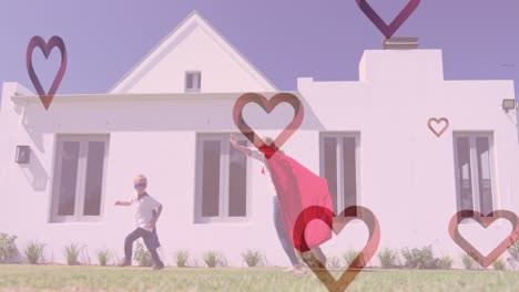 animation of hearts falling over caucasian woman and her son playing together in garden