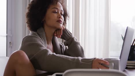 woman working on laptop and having coffee while sitting at table