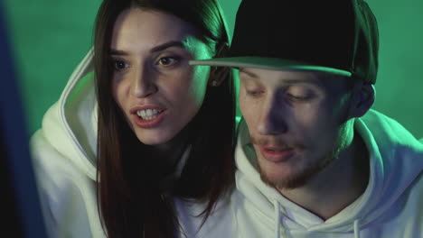 Portrait-of-modern-man-and-woman-using-a-computer-on-a-neon-light-colorful-background.-Close-up.