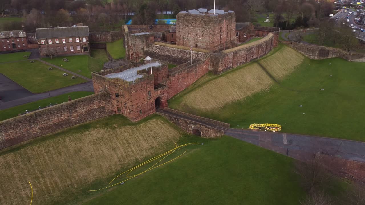 Cinematic aerial spinning round Carlisle Castle front gate with Union Jack Flag - Cumbria, England