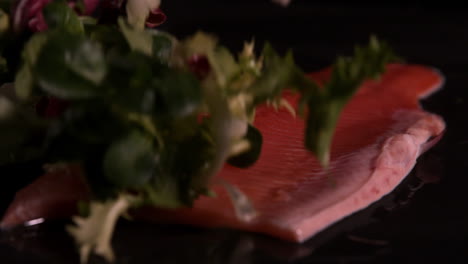 hojas de lechuga cayendo sobre filete de trucha fresca