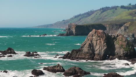 Static-drone-shot-of-waves-crashing-into-the-steep-rock-walls-of-northern-California