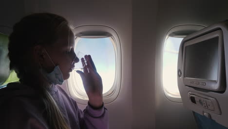 un niño bebe agua mientras vuela en un avión. la máscara protectora se baja. comidas a bordo del avión durante la pandemia de coronavirus