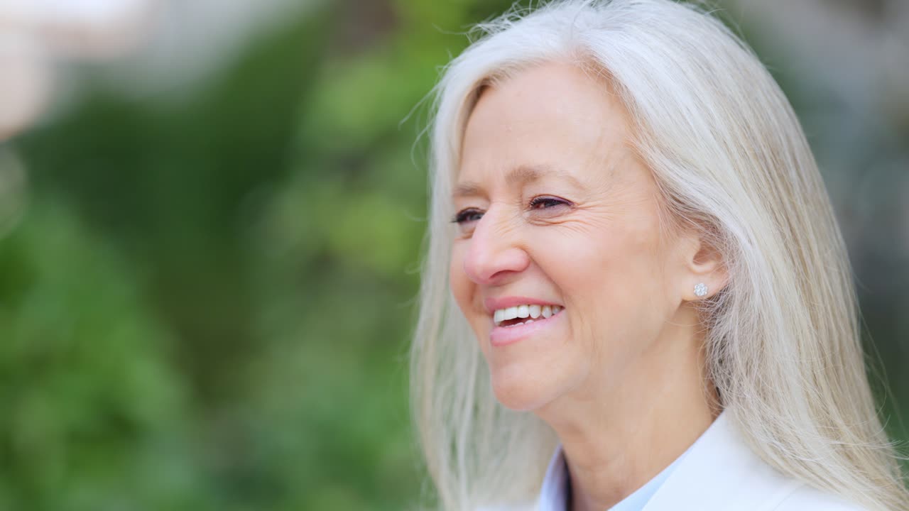 Portrait of a happy senior woman with white hair smiling outdoors