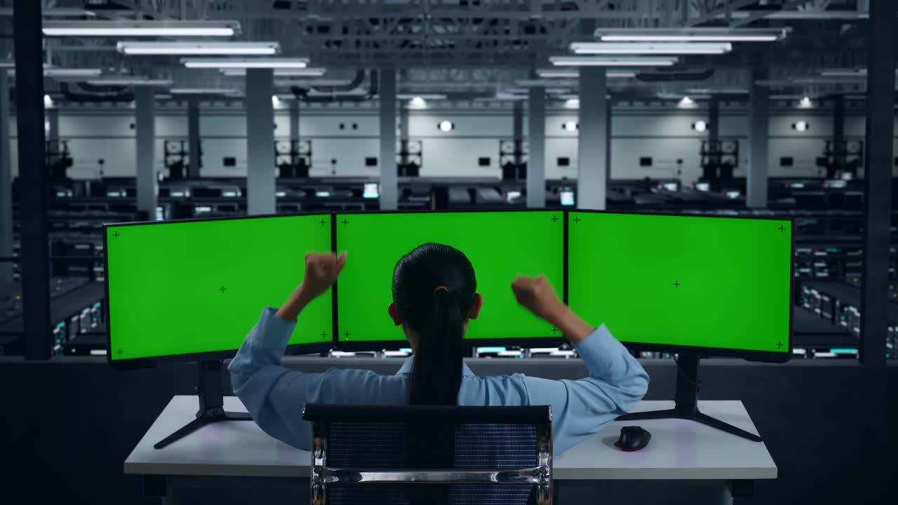 데이터 센터에서 모형 여러 컴퓨터 모니터와 함께 작업하는 동안 축하하고 춤을 추는 행복한 아시아 여성의 뒷면