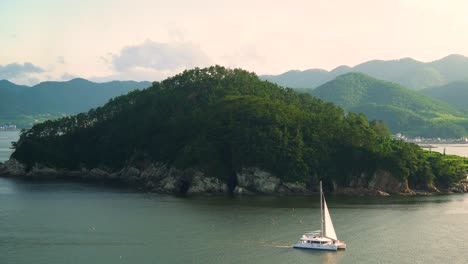 A-catamaran-sails-around-one-of-the-smaller-islands-in-South-Korea-near-Geoje-City-on-Geojedo-Island---tranquil,-picturesque,-scenic