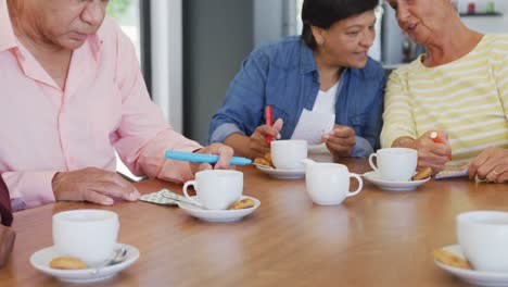 Happy-senior-diverse-people-drinking-tea-and-playing-bingo-at-retirement-home