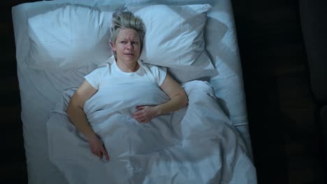 mujer molesta no puede dormir debido al ruido de los vecinos mientras está acostada en la cama en el dormitorio, vista superior