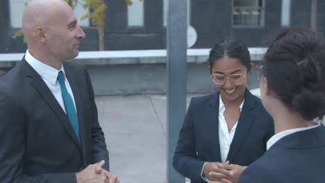 happy business team standing at office building, talking and laughing together