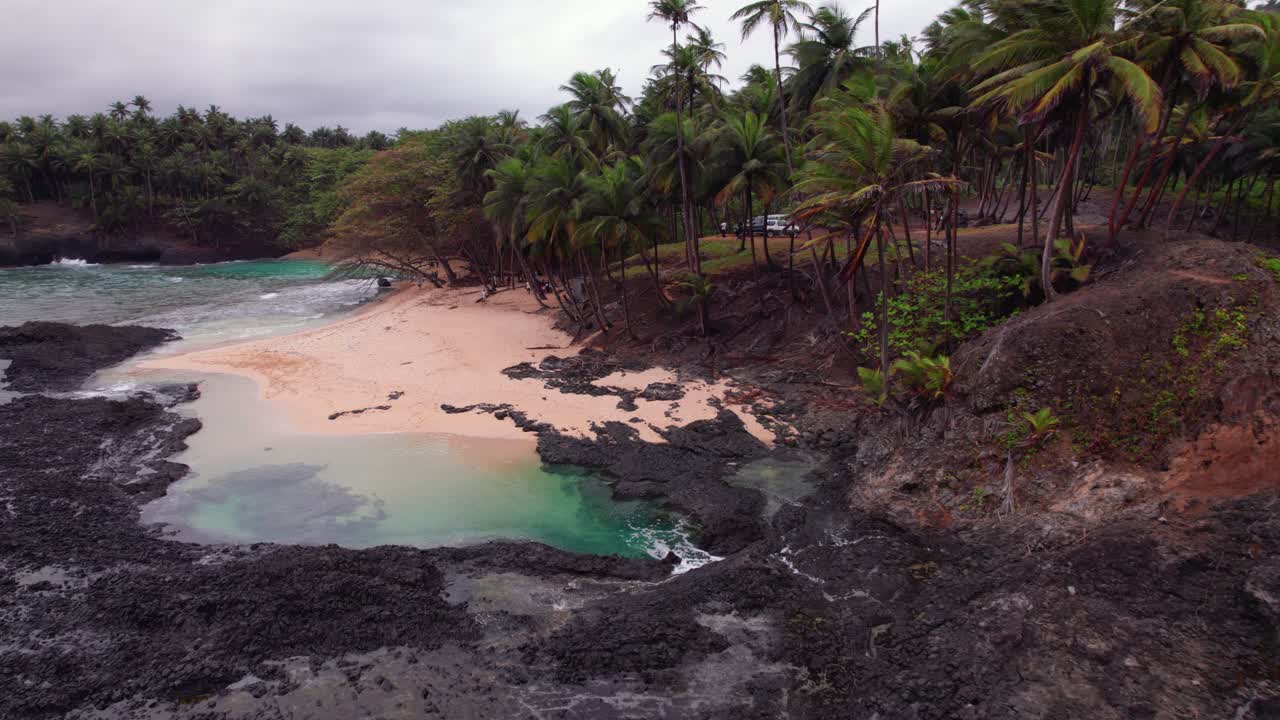 Stormy waves crash on Praia Piscina, São Tomé, a dramatic blend of wild ocean power and serene tropical beach landscape