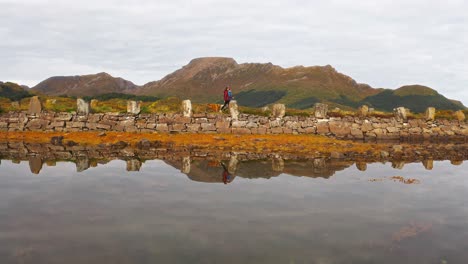 serene landscape in vestarelen, norway with mountains, a stone wall, and a reflective pool