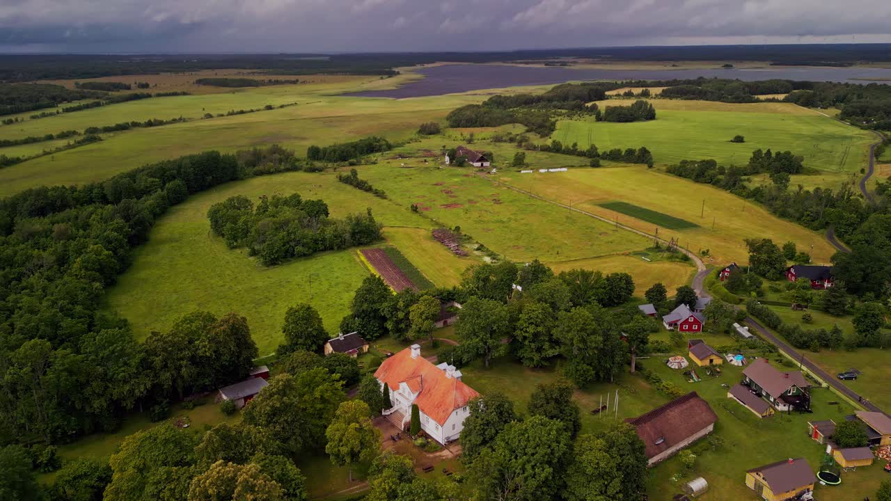 This aerial drone footage showcases Saare Manor, a historic estate in Noarootsi, Estonia, peacefully tucked into a lush green landscape with open fields, forest edges, and serene countryside views.