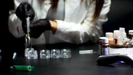 doctor in black gloves taking vaccine with syringe of a vial with pills on the table