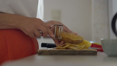 Primer-Plano-De-Una-Mujer-Pelando-Patatas-En-La-Encimera-De-La-Cocina