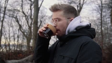 Young-caucasian-male-drinking-hot-coffee-from-a-sustainable-keep-cup-out-of-glass