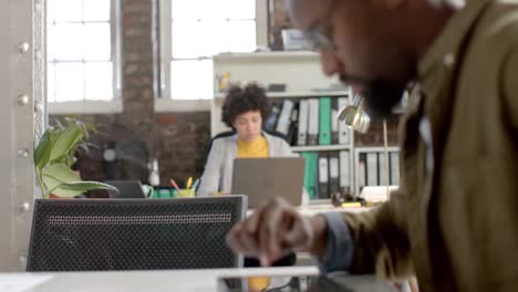 focused diverse colleagues using tablet and laptop in office in slow motion